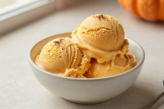 Two generous scoops of pumpkin pie ice cream in a shallow ceramic bowl, softly melting at the edges