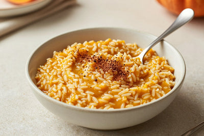 Creamy pumpkin spice rice pudding in a small ceramic bowl with a spoon, garnished as in the recipe