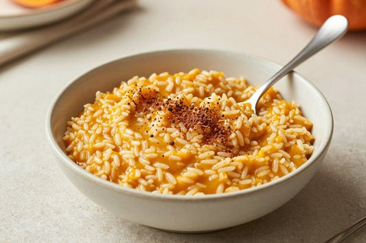 Creamy pumpkin spice rice pudding in a small ceramic bowl with a spoon, garnished as in the recipe
