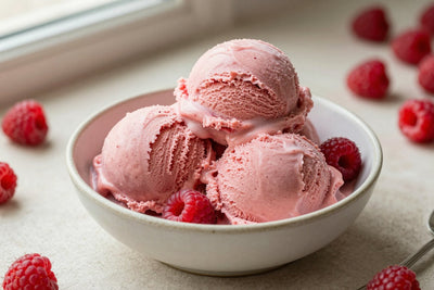 Two generous scoops of raspberry ice cream in a shallow ceramic bowl, softly melting at the edges