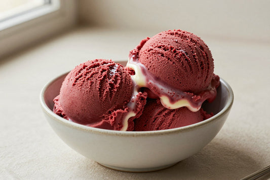 Two generous scoops of red velvet ice cream in a shallow ceramic bowl, softly melting at the edges
