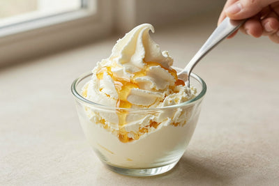 A generous swirl of ricotta & honey gelato in a small glass cup with a flat gelato spade