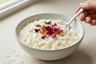 Creamy rose rice pudding in a small ceramic bowl with a spoon, garnished as in the recipe
