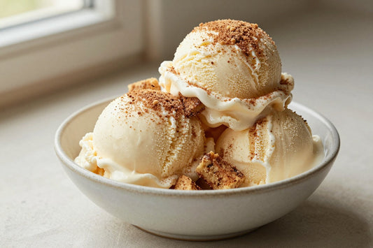 Two generous scoops of snickerdoodle ice cream in a shallow ceramic bowl, softly melting at the edges