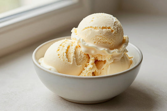 Two generous scoops of vanilla cheesecake ice cream in a shallow ceramic bowl, softly melting at the edges